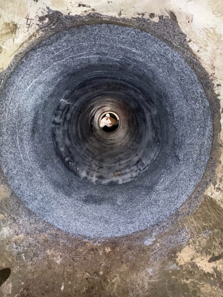 Completed carbon-fiber pipe rehabilitation with topcoat applied, crew member at the far end for scale